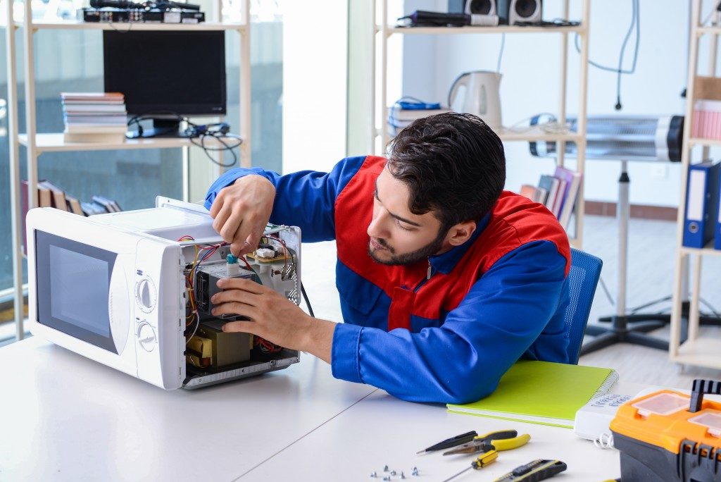 Maintenance man repairing microwave