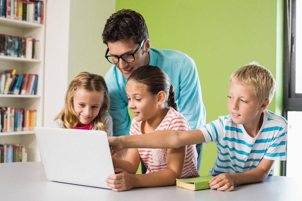 kids and their dad looking at the laptop