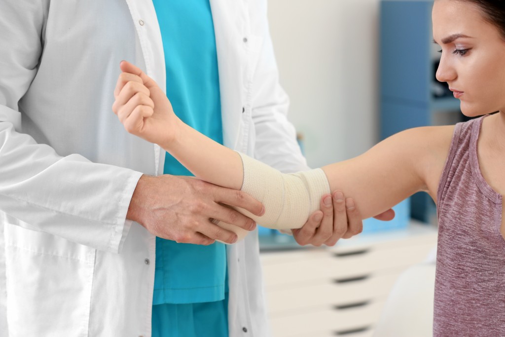 Orthopedic doctor checking elbow of teenager