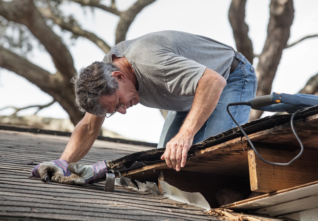 man repairing a damaged roof