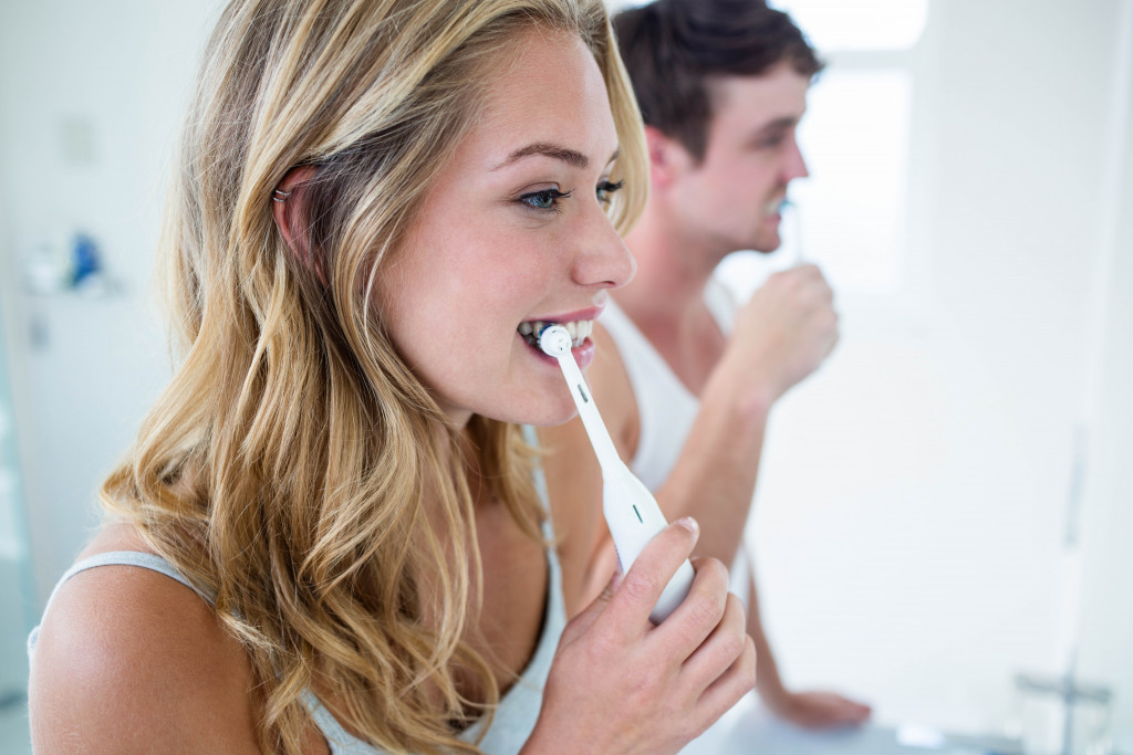man and woman brushing their teeth