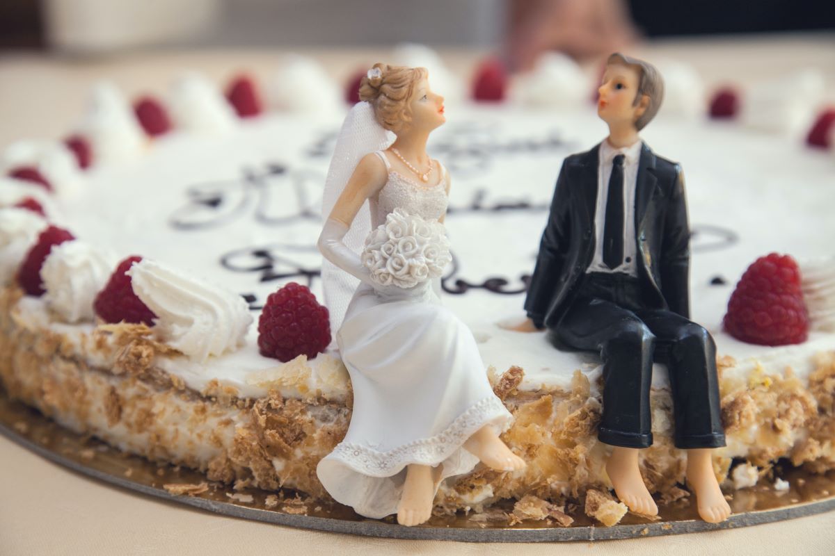 Bride and groom figurine sitting on cake