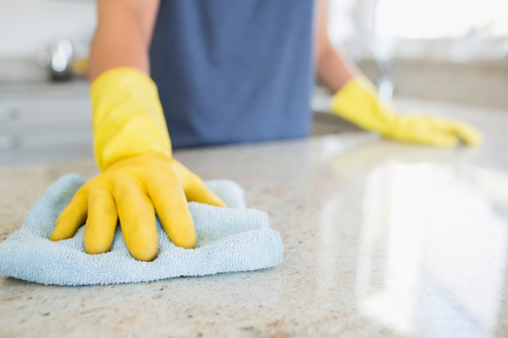 cleaning a table countertop with a linen with yellow gloves