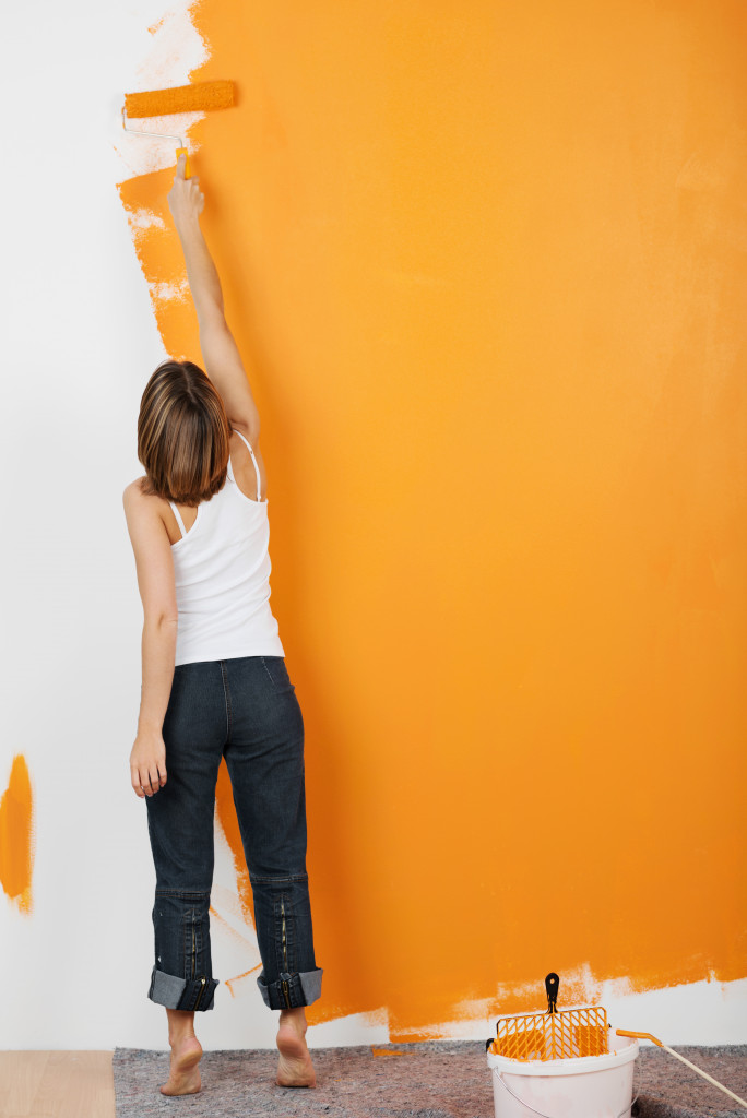 woman painting the wall orange