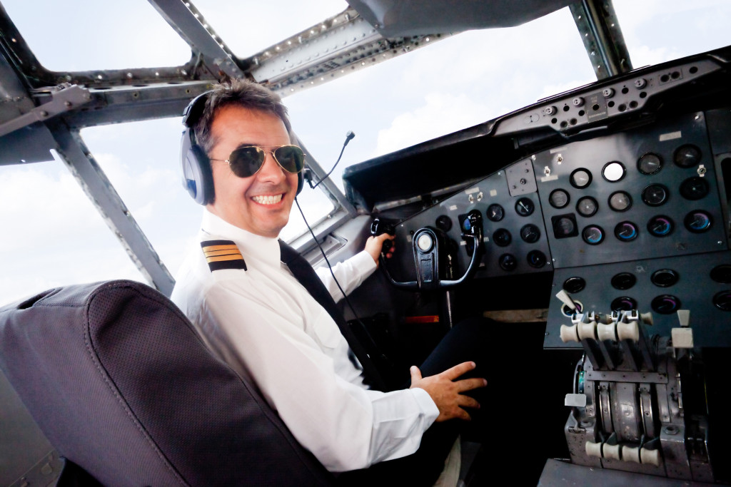 Male pilot sitting in an airplane cabin flying and smiling