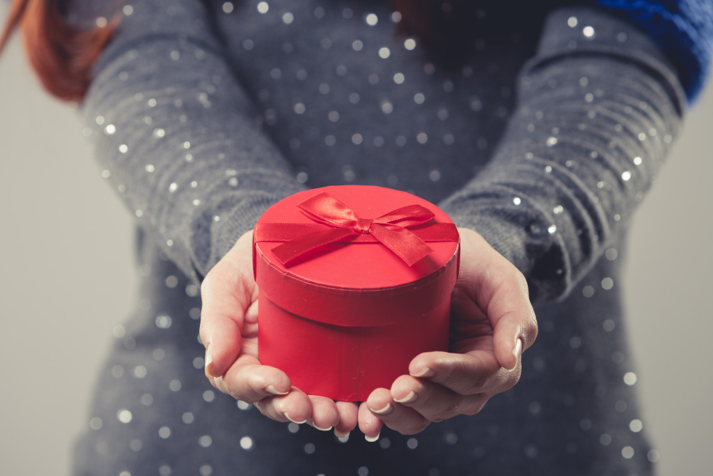 A woman holding a small red gift box with a ribbon