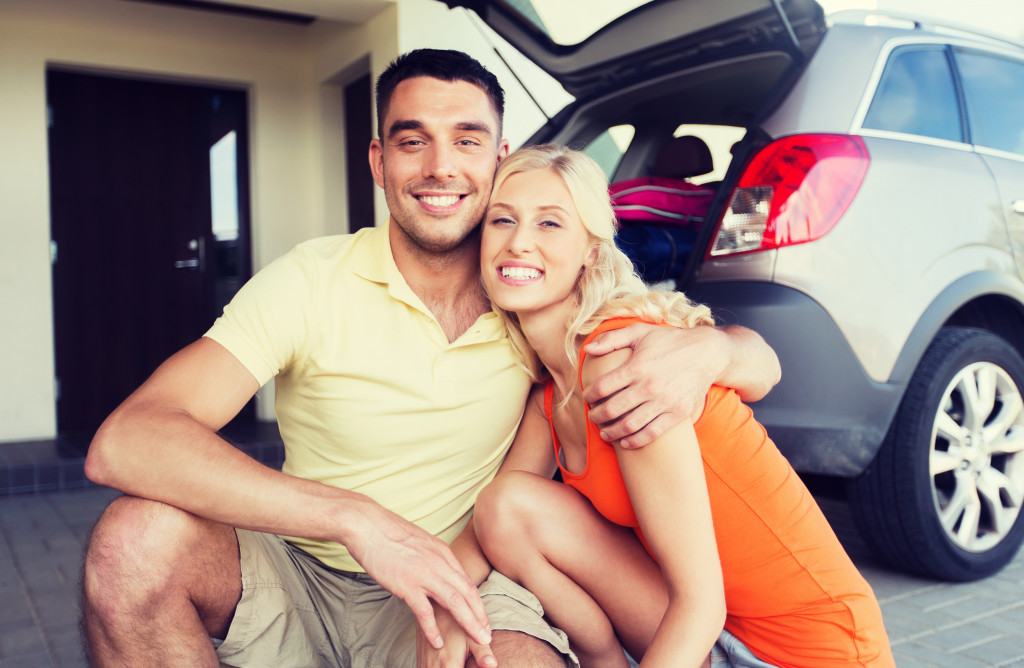 couple taking a photo with their parked car at home