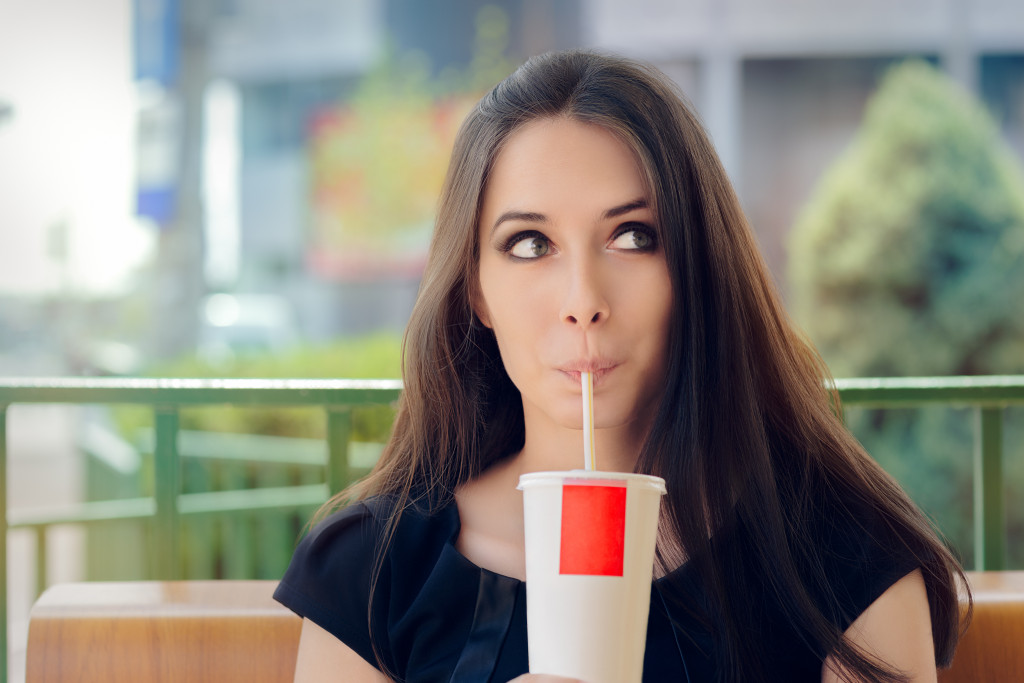 a girl looking away from camera drinking soda